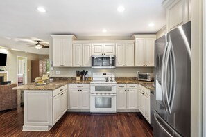 A modern kitchen with white cabinetry, stainless steel appliances, and a granite countertop.
