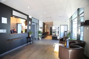 A modern hotel lobby with a reception desk, seating area, and a vending machine.