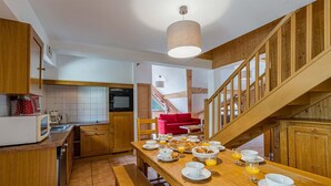 A kitchen with wooden cabinets, a red chair, and a breakfast table set with plates, glasses, and orange juice.