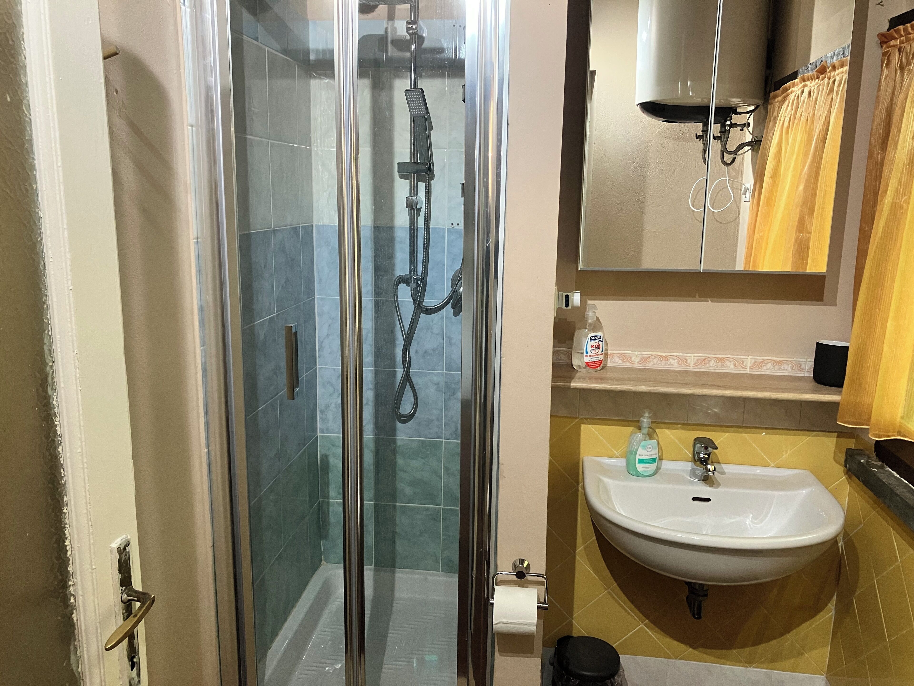 Ein Badezimmer mit einer Duschkabine, einem Waschbecken und einem Spiegel darüber.