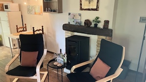 A cozy living room with two armchairs, a small table with drinks, a fireplace, and a kitchen area in the background. - 1 Bed Studio - Pets - Terrace - Parking (Borgo Val di Taro)