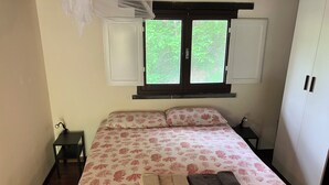 A bedroom with a bed, two nightstands, a wardrobe, and a window with open shutters. - 1 Bed Studio - Pets - Terrace - Parking (Borgo Val di Taro)