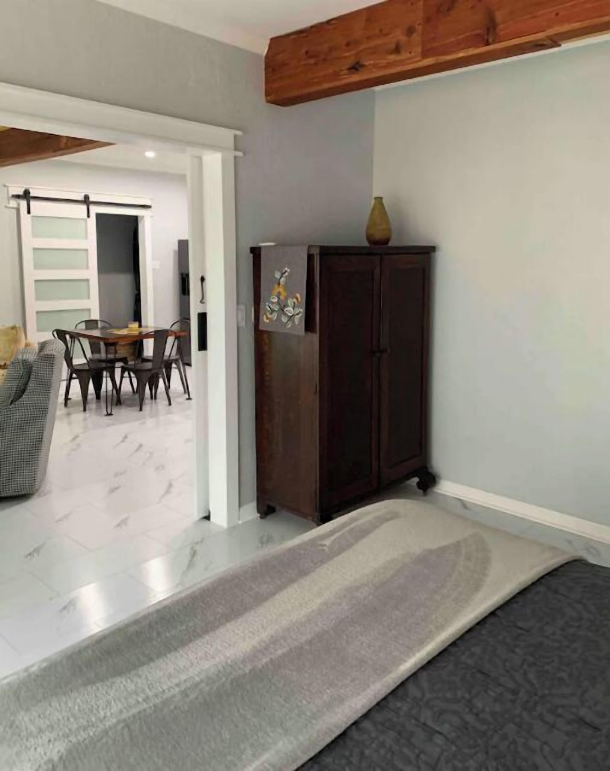 A room with a dining table and chairs, a dark wooden cabinet, and a grey carpet.