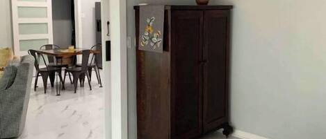 A room with a dining table and chairs, a dark wooden cabinet, and a grey carpet.