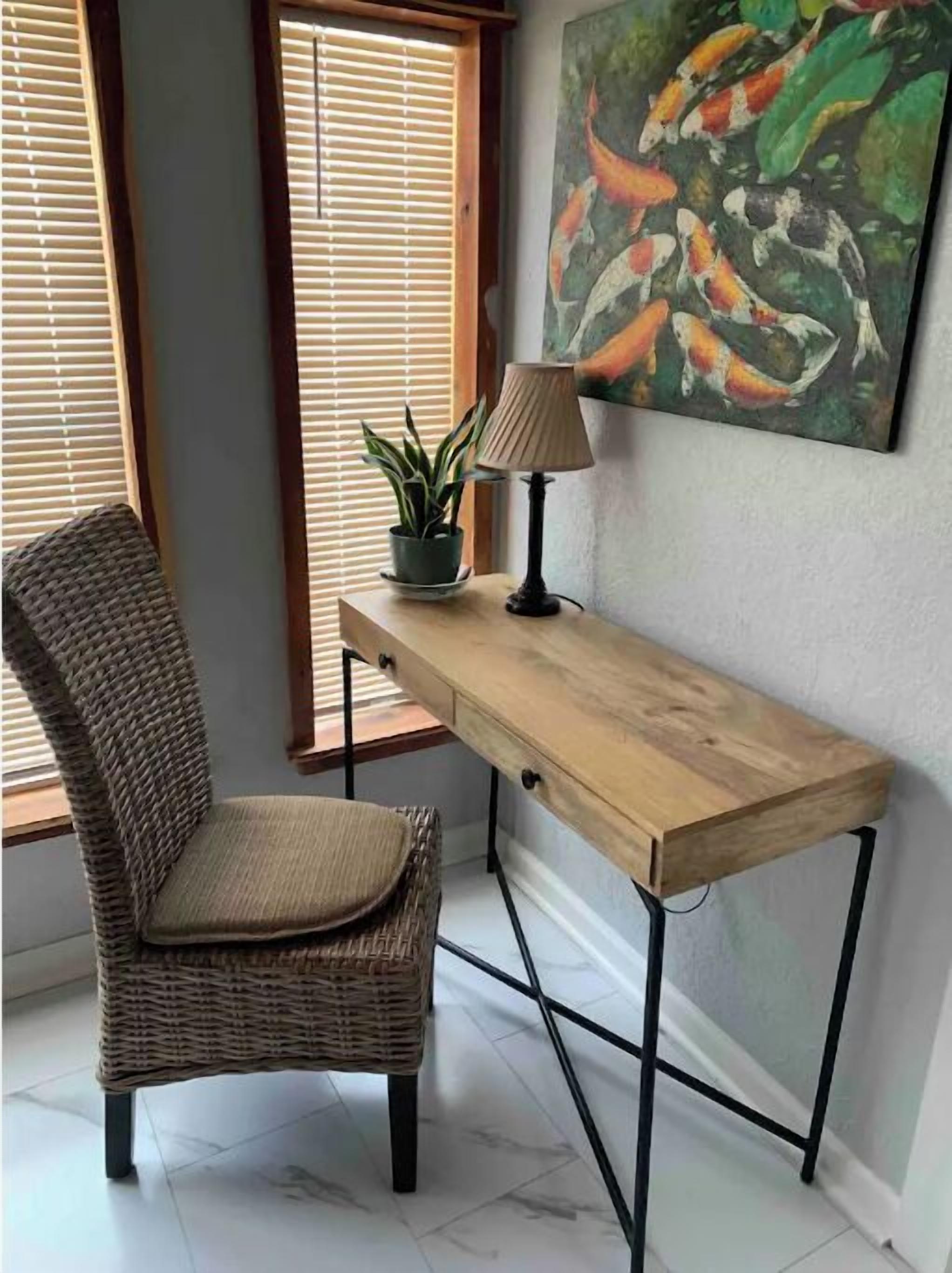 Ein Korbstuhl, ein Holztisch, eine Lampe, ein Blumentopf und ein Bild von Koi-Karpfen.
