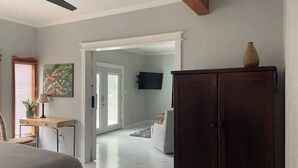 A bedroom with a bed, a desk, a wardrobe, a ceiling fan, and a painting. - Stylish, comfortable, and private Guest House. (Eastman)