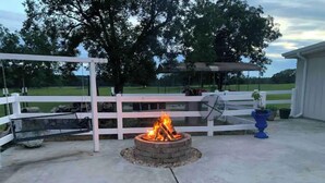 An outdoor patio with a fire pit, white fence, and a potted plant. - Stylish, comfortable, and private Guest House. (Eastman)