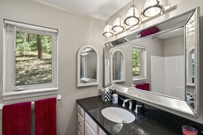 A bathroom with a large mirror, a sink, and a window with a view of a forest. - Pet Friendly, Solitude, 15 Mins to Vallecito! (Bayfield)