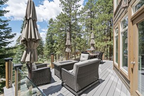 A deck with wicker furniture, including sofas and a table, surrounded by tall trees and a glass railing. - Pet Friendly, Solitude, 15 Mins to Vallecito! (Bayfield)