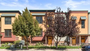 A row of townhouses with a brick facade, green awnings, and a small front yard with trees. - Excellent Location- Downtown Carbondale on Main St.! (Carbondale)