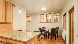 A kitchen with wooden cabinets, a granite countertop, and a dining area with a table and chairs. - Excellent Location- Downtown Carbondale on Main St.! (Carbondale)