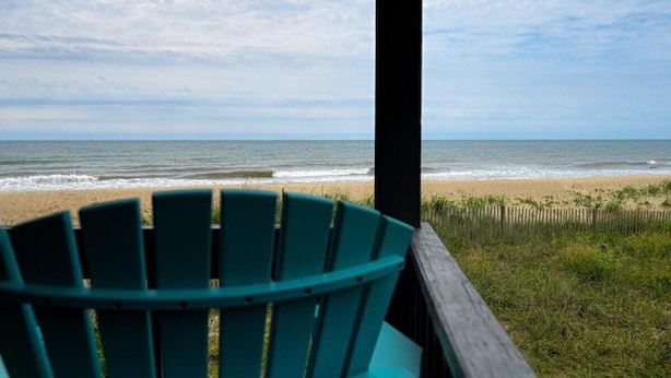 Uitzicht op de oceaan vanaf een overdekt terras, met een groene stoel op de voorgrond.