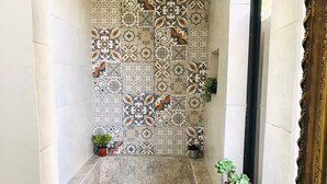 A narrow bathroom with a tiled shower wall, a bathtub, and steps leading up to it. There are potted plants on the steps. - Junior Suite Mesh View with view of the mountains (Rionegro)