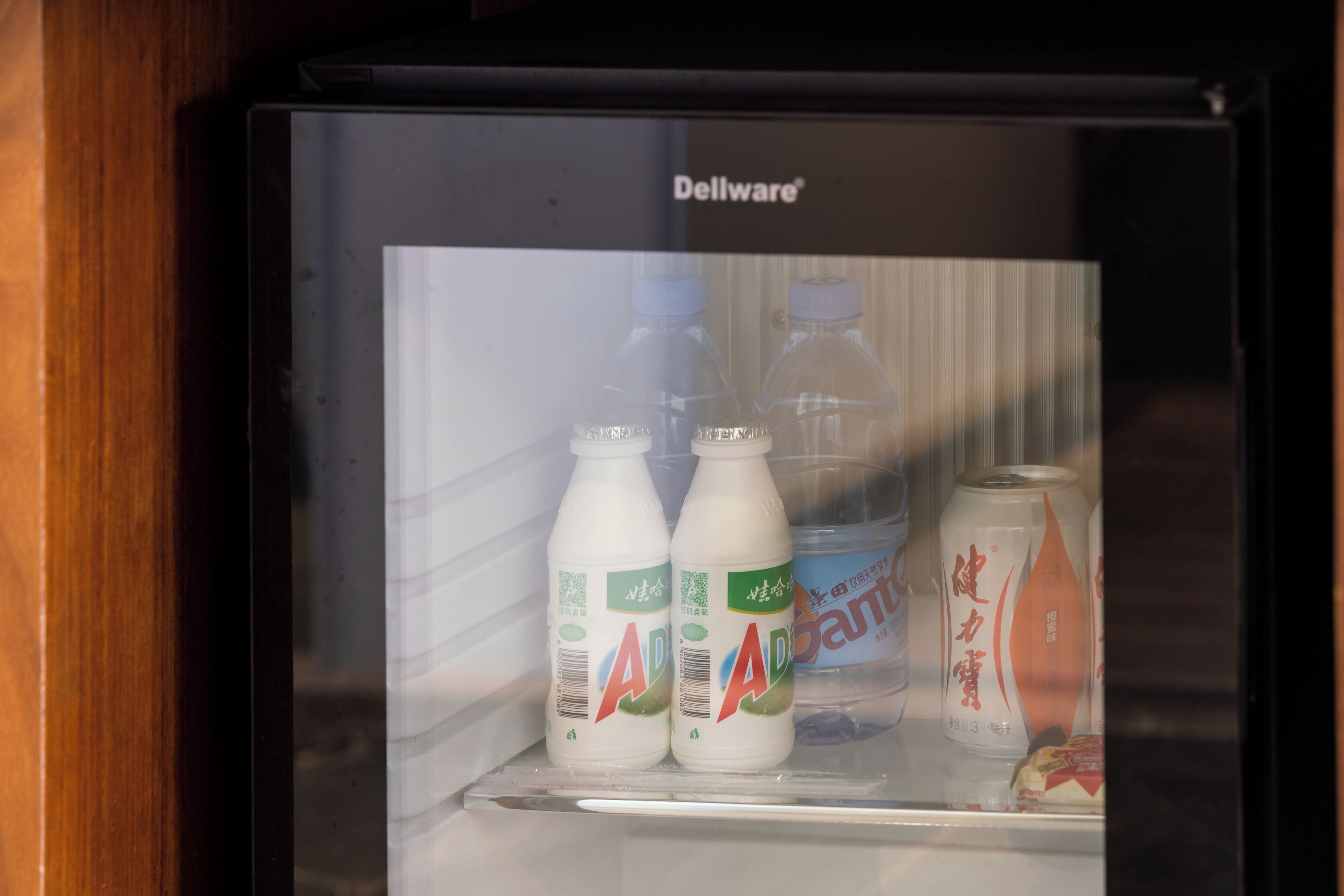 Un refrigerador con una botella de agua y una lata de refresco.
