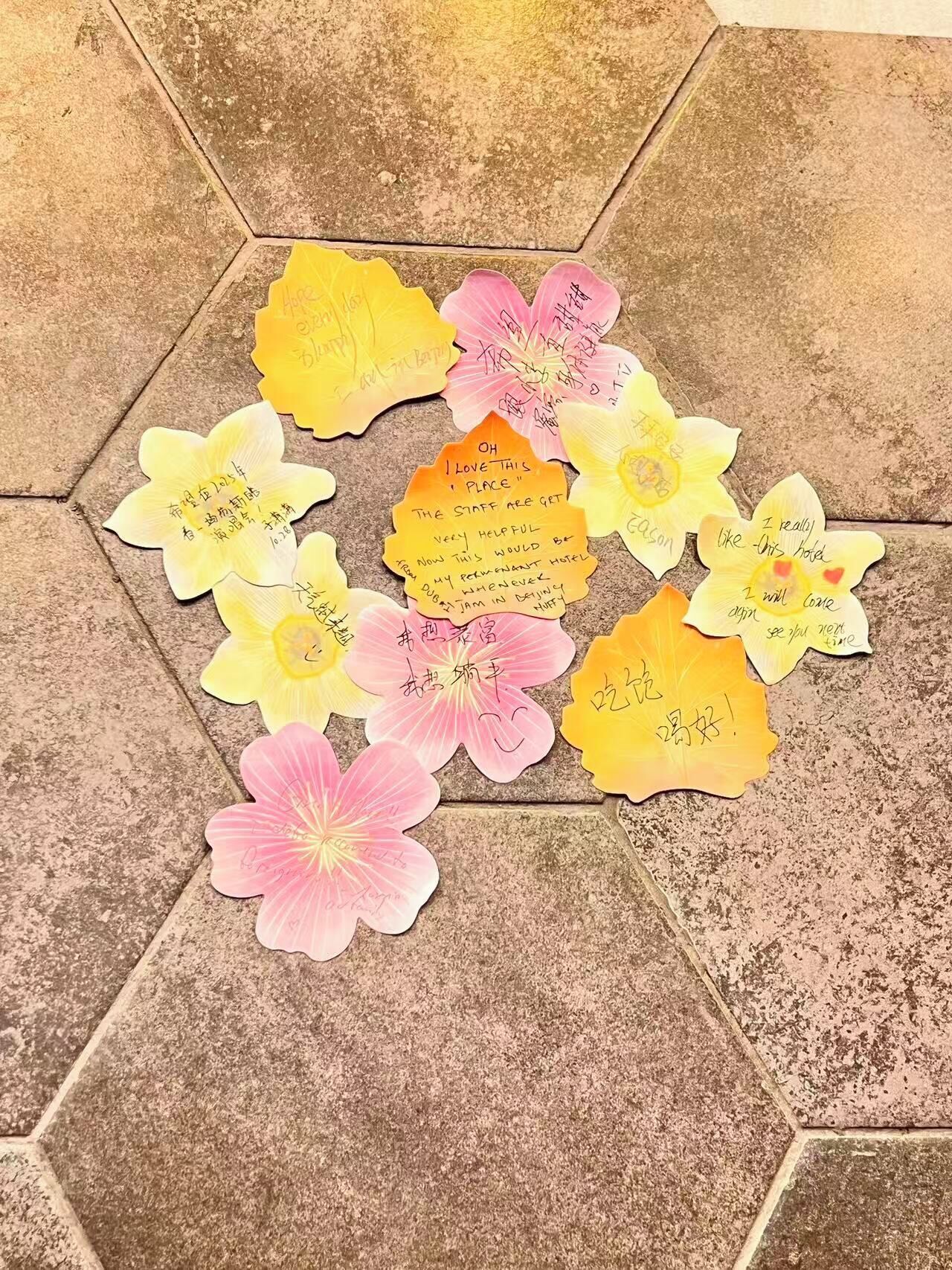 Un suelo de baldosas hexagonales con varias notas con forma de flor que contienen mensajes escritos a mano.