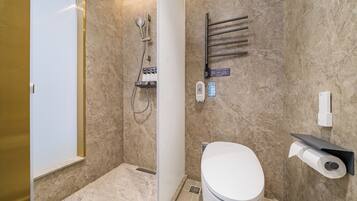 A bathroom with a shower, toilet, towel rack, and a toilet paper holder.