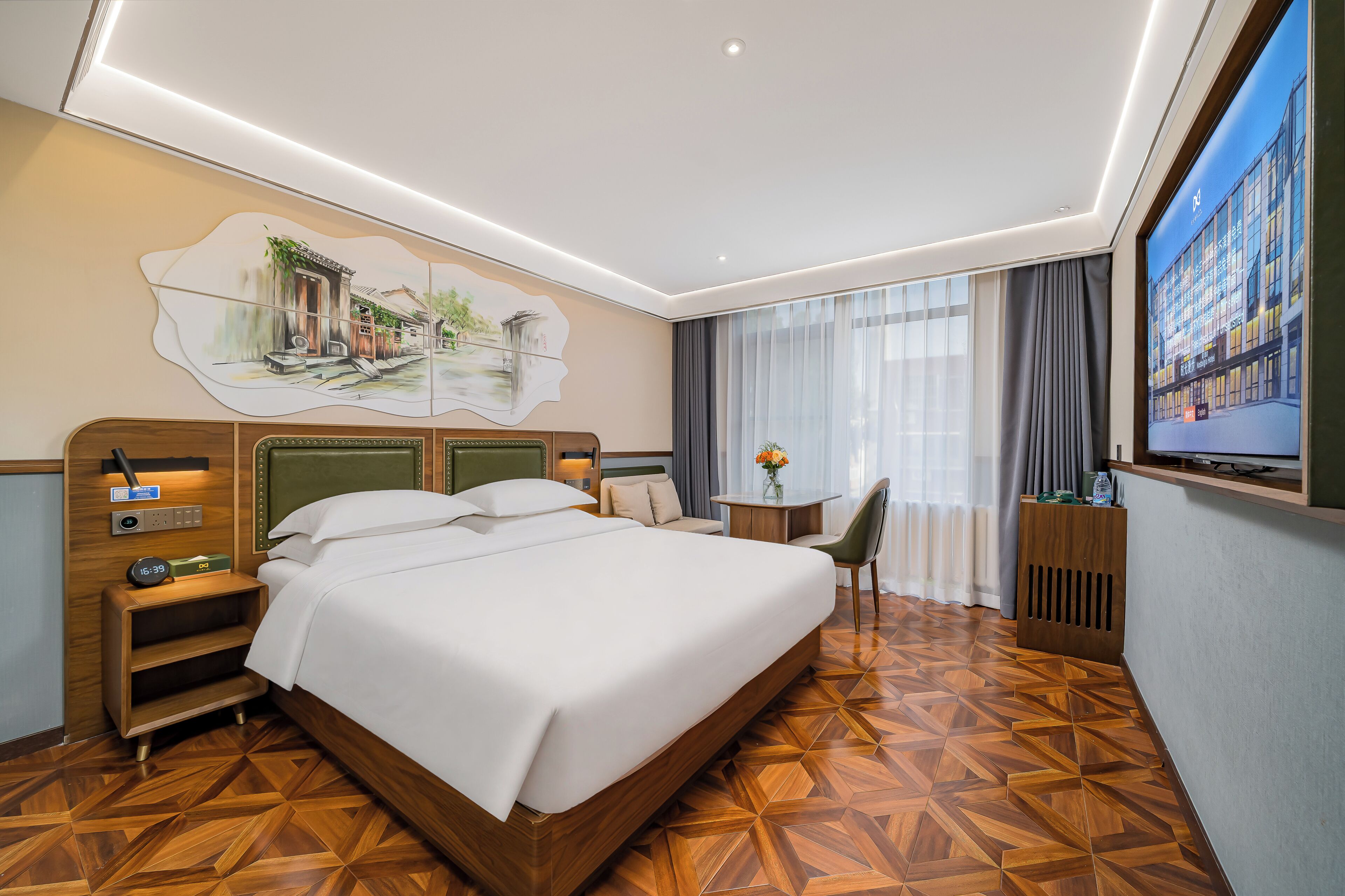 Una habitación de hotel con una cama grande, mesitas de noche, un escritorio, una silla, un televisor y un cuadro en la pared.