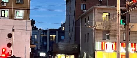 Straßenansicht mit Gebäuden, einer Fußgängerampel und Fahrzeugen.