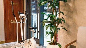 Een kamer met een hometrainer, een plant in pot en een houten deur met tekst.