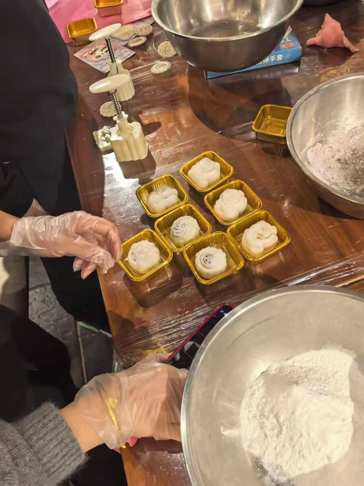 Una persona preparando comida, concretamente dumplings, sobre una mesa de madera con diversas herramientas y ingredientes de cocina.