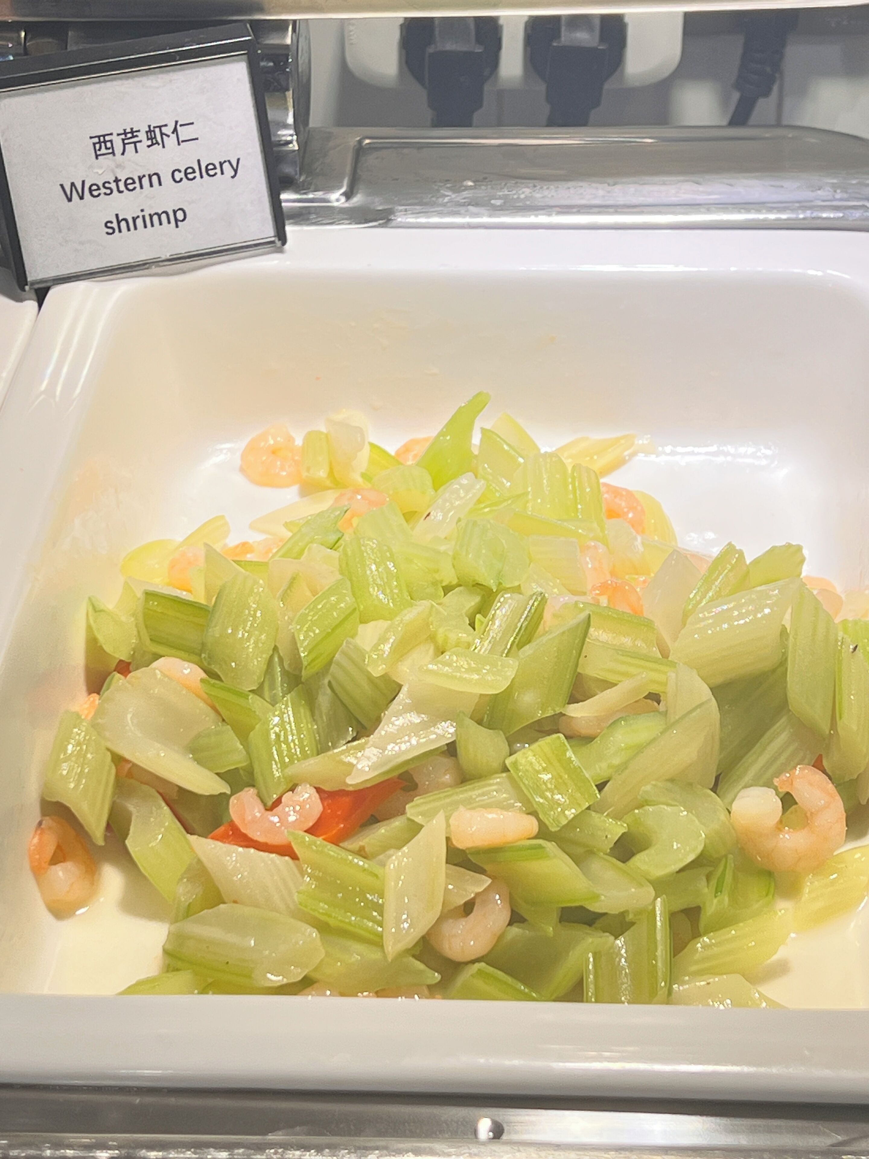 A buffet dish labeled "Western celery shrimp" with chopped celery and shrimp.