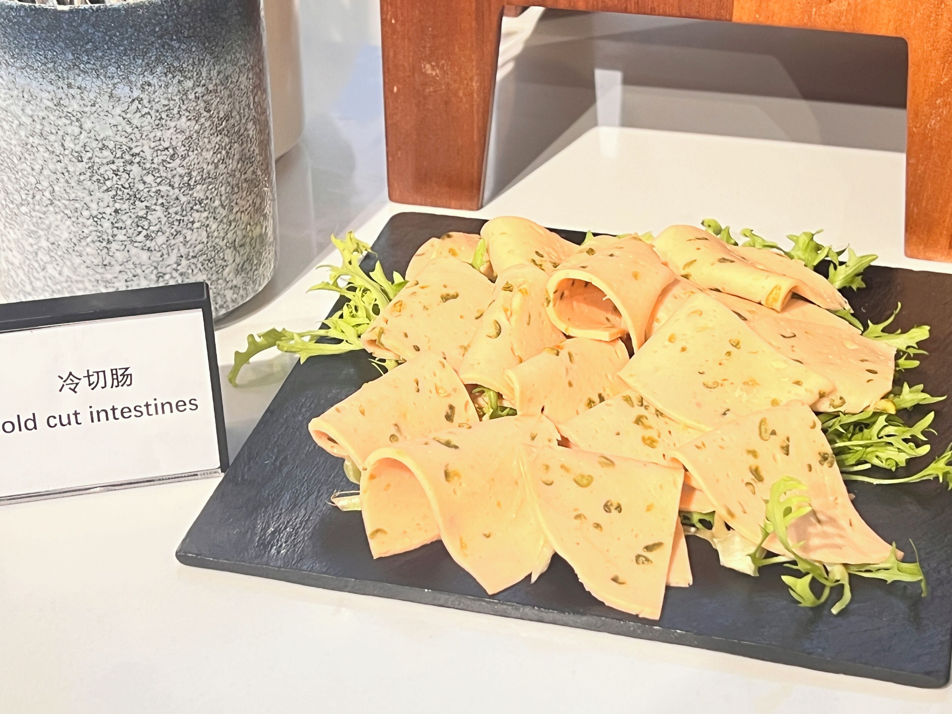Une assiette de charcuterie, comprenant des intestins, avec une pancarte écrite dans une langue étrangère.