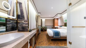 Hotelkamer met een groot bed, een badkamer met een grote spiegel, een bureau en uitzicht op een brug.