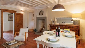 A dining area with a white table set for four, a wooden chair, and a hanging pendant light. - Lovely apartment for 4 guests with WIFI, A/C (Cortona)