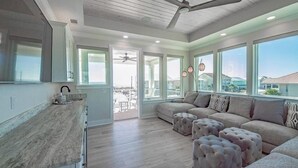 A spacious living area with a large window, a ceiling fan, and a view of the outside. - Beach Country 7 BR/ 7.5 House w/ Heated Pool (Navarre Beach)