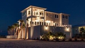 A multi-story beachfront property with balconies, a covered patio, and a sandy beach in the foreground. - Beach Country 7 BR/ 7.5 House w/ Heated Pool (Navarre Beach)