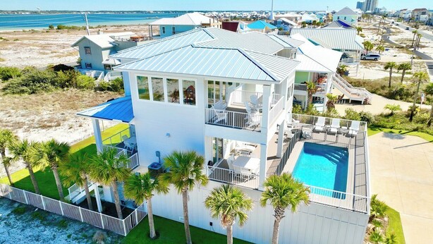 A multi-story beachfront property with a pool, balconies, and palm trees. - Beach Country 7 BR/ 7.5 House w/ Heated Pool (Navarre Beach)