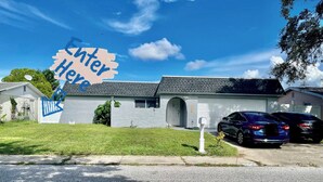 A single-story house with a garage, a driveway, and two parked cars. - Studio at family home  recently remodeled, free wifi ,and live tv  (Port Richey)