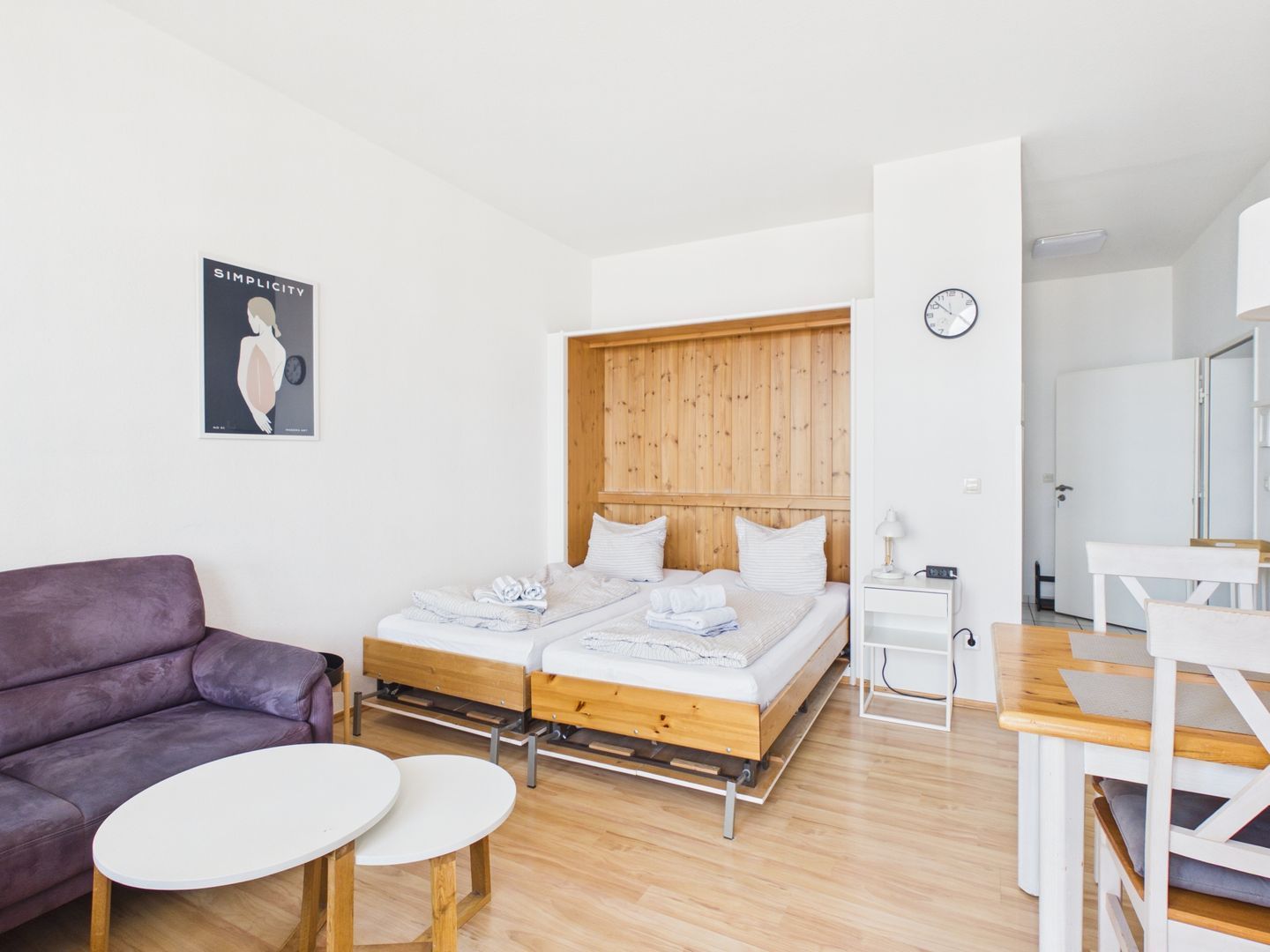A modern room with a wooden headboard bed, a purple sofa, and a small white table.