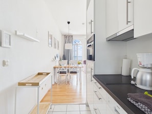 Una cocina moderna con armarios blancos, encimera de madera y vistas al exterior.