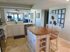 A kitchen with white cabinets, a wooden island, and a dining area with a chair.