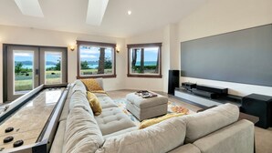 En moderne stue med et shuffleboard-bord, en stor sofa og et fladskærms-tv.