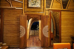 A wooden room with a large door leading to a balcony.