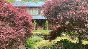A traditional Japanese-style building with a wooden exterior and a thatched roof. - Charming Log Cabin Retreat with Flower Garden (McKenzie)