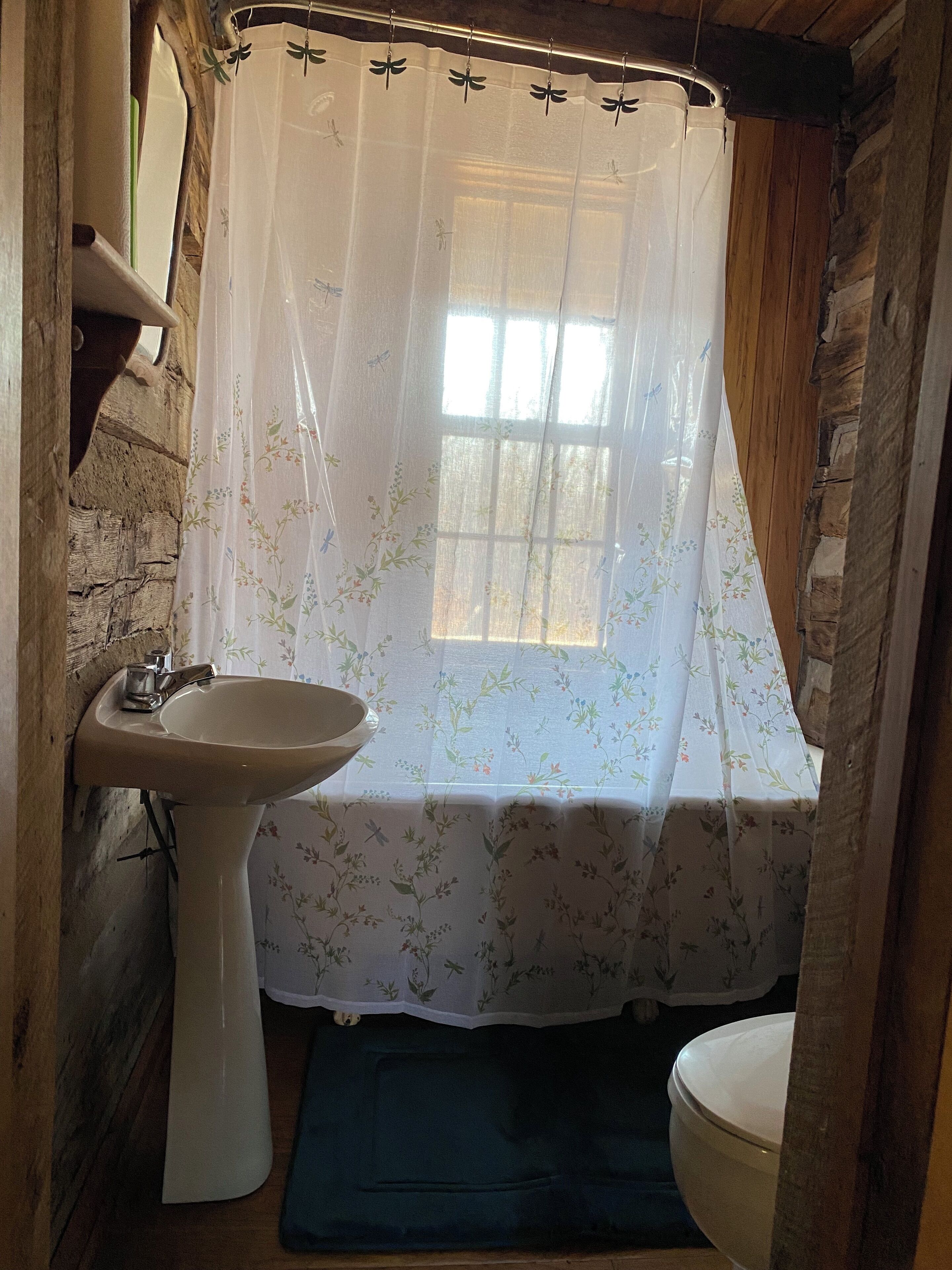 A bathroom with a wooden interior, a white sink, a toilet, and a shower curtain with floral patterns.