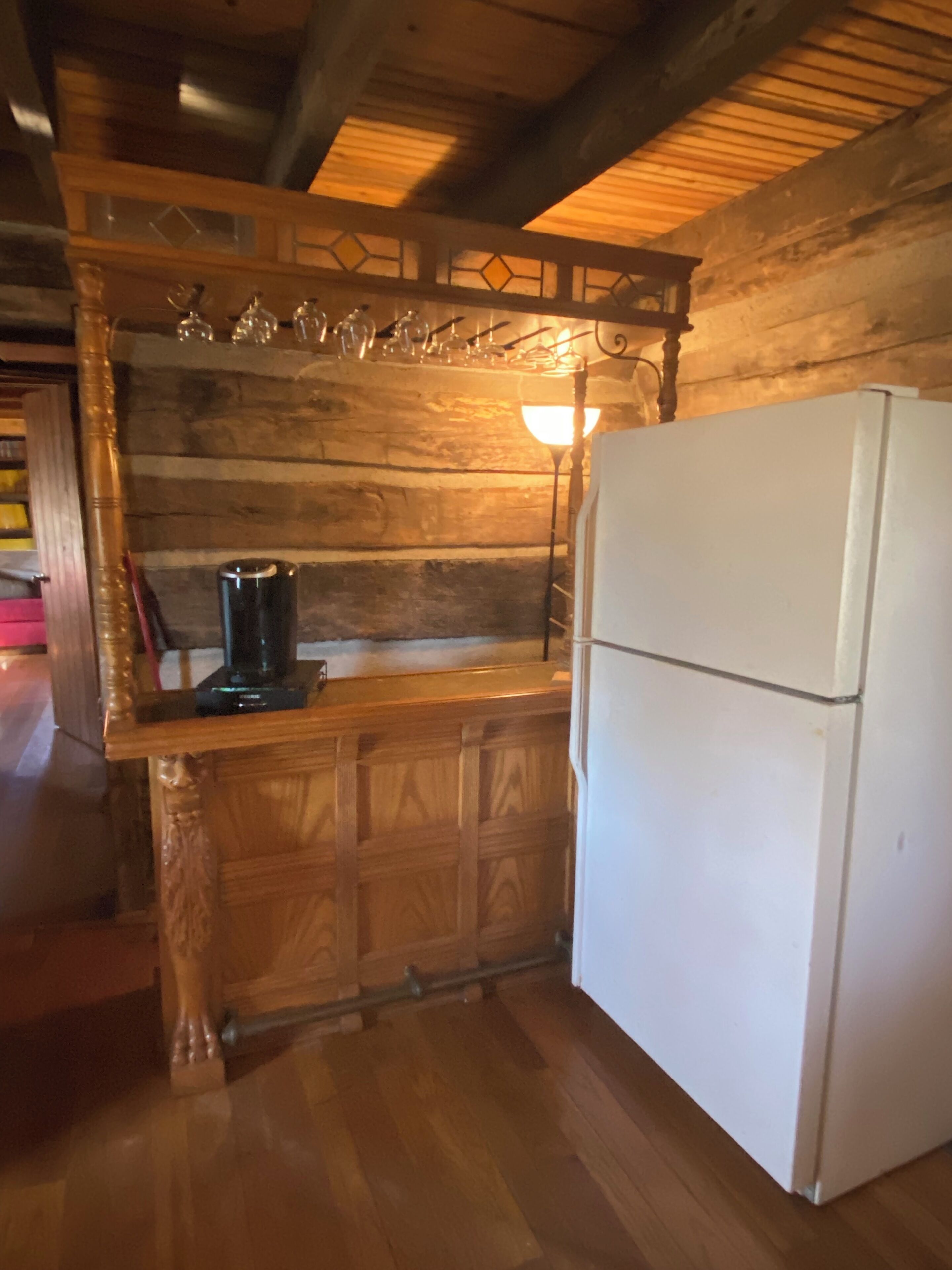 Een keuken met houten kastjes, een witte koelkast en een aanrecht met een koffiezetapparaat en glazen.