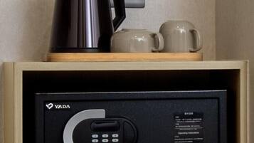 Un mini-bar comprenant une machine à café, deux tasses et un panneau de commande avec un clavier et des instructions.