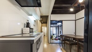 Een moderne keuken met een centraal eiland, een eethoek met een tafel en stoelen, en een doorkijk naar een andere ruimte.
