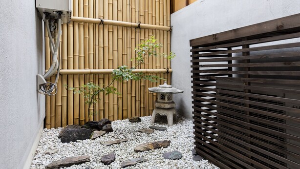 Een traditionele Japanse tuin met een bamboomborduurwerk, een stenen lantaarn en een kleine boom.