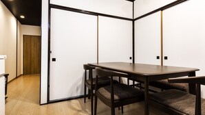 Een moderne kamer met een houten vloer, een donkerbruine tafel en bijpassende stoelen.