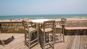 A wooden deck with a round table and chairs overlooking a beach. - OCEANFRONT, 4 BRs, Ocean Views, NP13-2, Summer Wind (Duck)