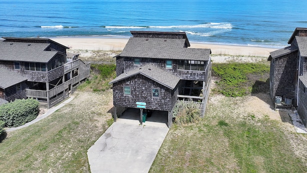 A beachfront property with multiple wooden cabins, a sandy beach, and the ocean in the background. - OCEANFRONT, 4 BRs, Ocean Views, NP13-2, Summer Wind (Duck)