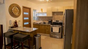 Una cocina moderna con una isla central, electrodomésticos de acero inoxidable y un reloj decorativo.
