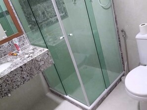 Bathroom features a glass-enclosed shower, toilet, and personal care area with a marble countertop.