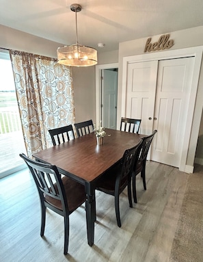 A dining area with a wooden table and chairs, a hanging light fixture, and a 'hello' sign on the wall. - Relaxing Entire House in Ankeny, IA (Bondurant)