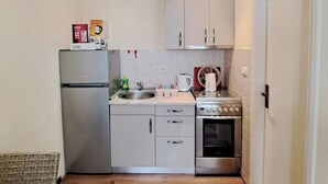Eine kleine Küche mit Kühlschrank, Spüle, Herd und Backofen.